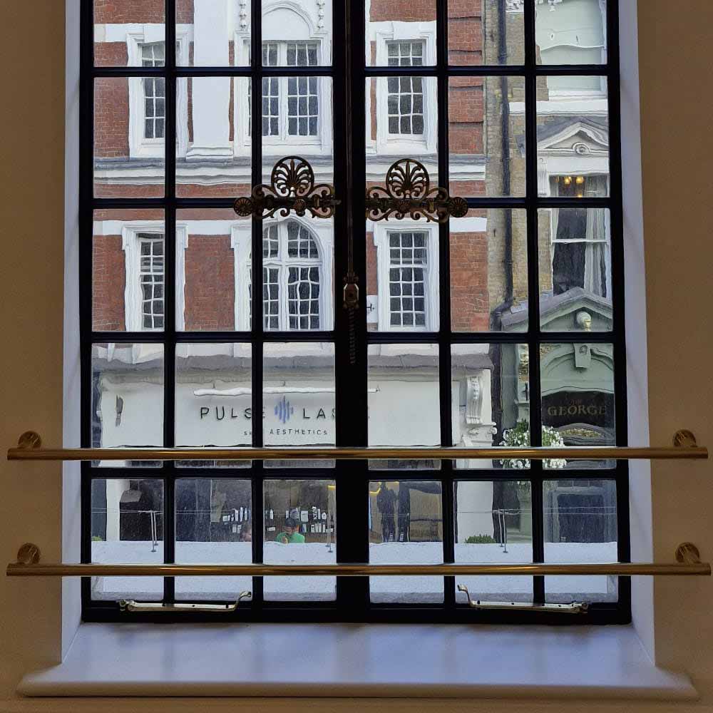 Refurbished historic metal window with detailed brass ironmongery