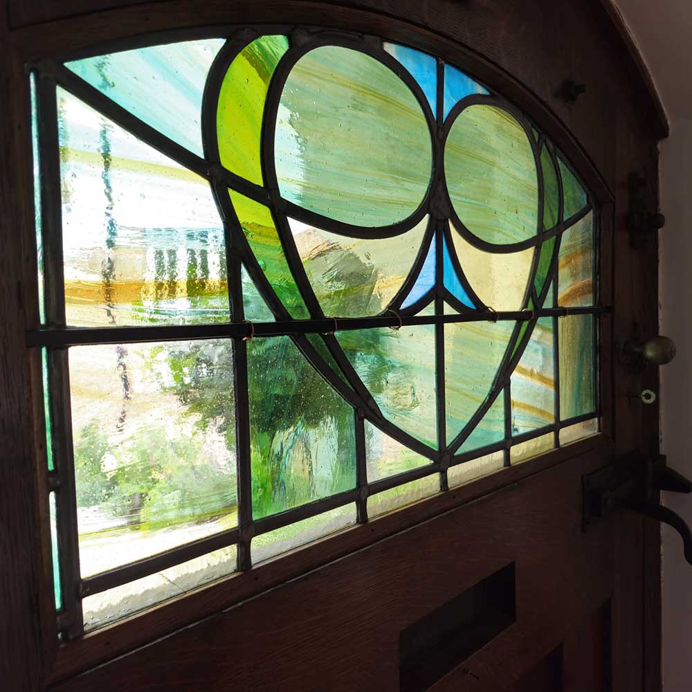Restored stained glass window featuring an owl design in the top half of a door