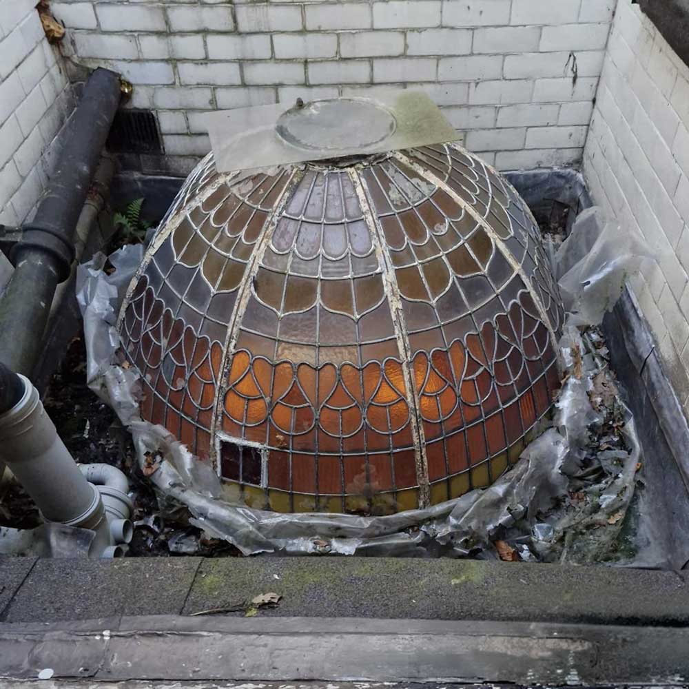 A deteriorated leaded stained glass dome skylight in situ on a rooftop
