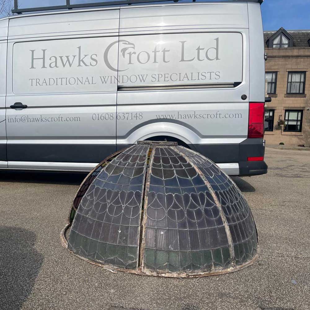 The disassembled leaded stained glass dome from Rookery Hall Hotel resting on a car park surface in front of a Hawkscroft Ltd Traditional Window Specialists van, ready for transportation to the workshop for restoration