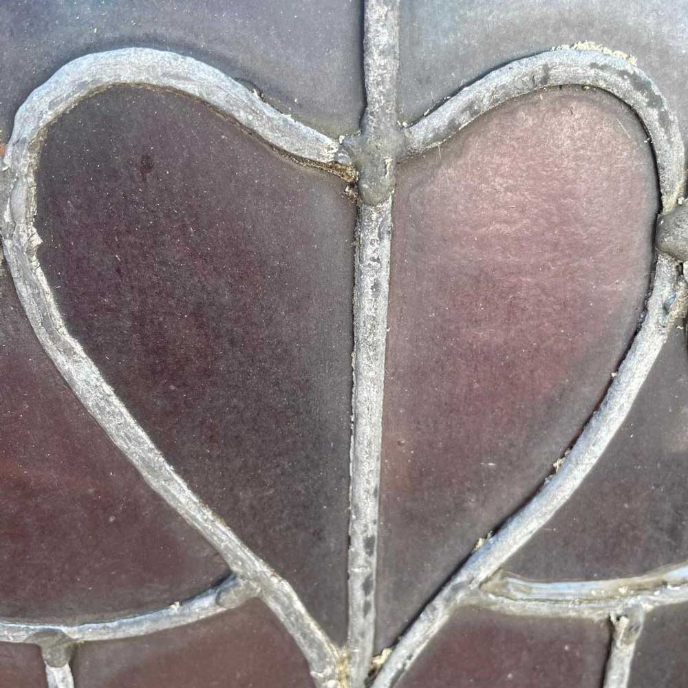 Close-up of heart-shaped leaded glass motifs in deep burgundy glass set within a lead came framework, showing the decorative Victorian design detail of the Rookery Hall stained glass dome