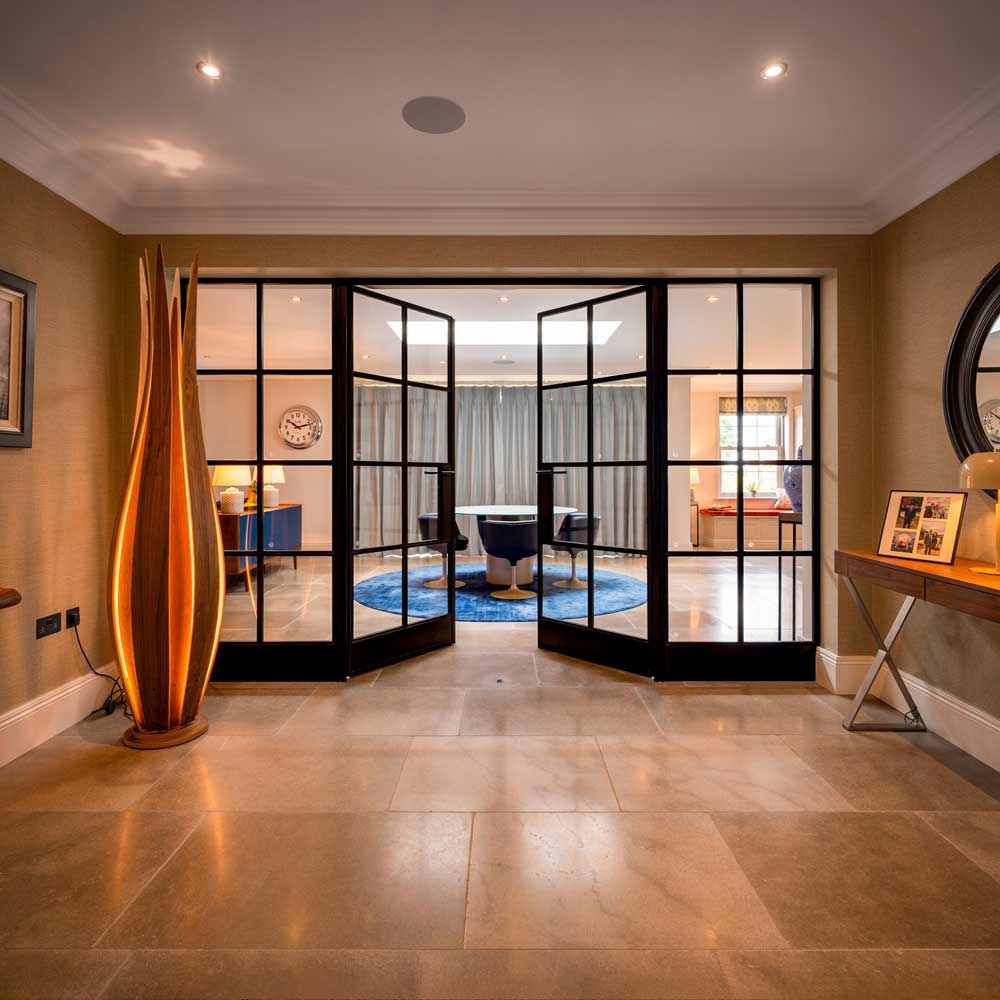Symmetrical view of black metal internal glazed doors standing open into a reception room