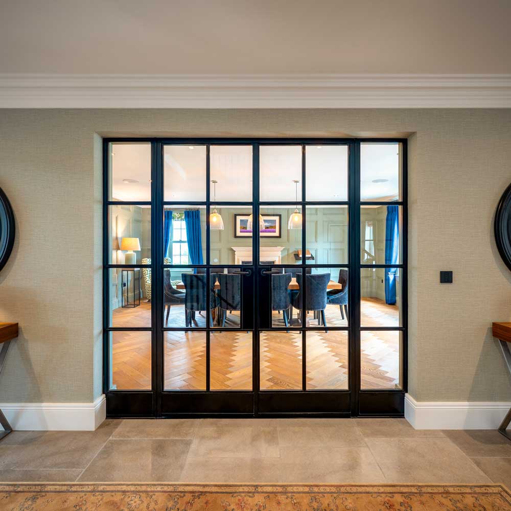 Symmetrical front-on view of closed black metal internal glazed doors leading into a formal dining room